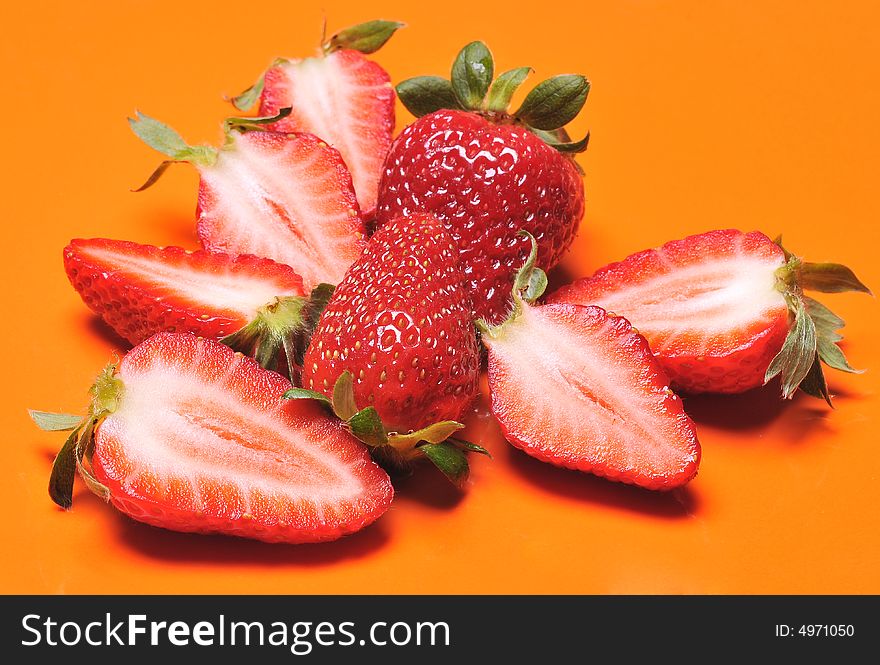 Close up of a group of fresh, succulent strawberries in orange background