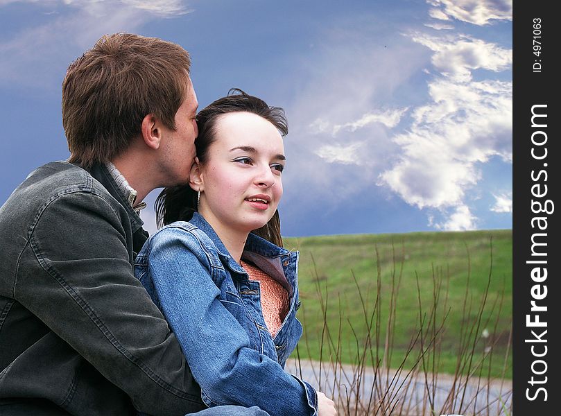 Guy and girl sits on a grass on a background of the sky. Guy and girl sits on a grass on a background of the sky