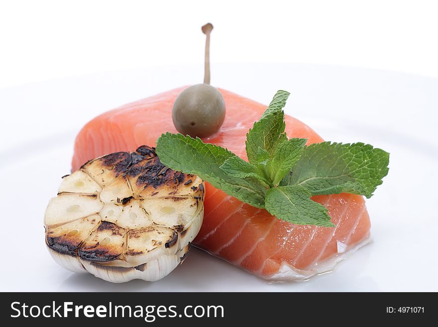 Fresh salmon, garlic and green on a plate. Isolated on a white background. Fresh salmon, garlic and green on a plate. Isolated on a white background