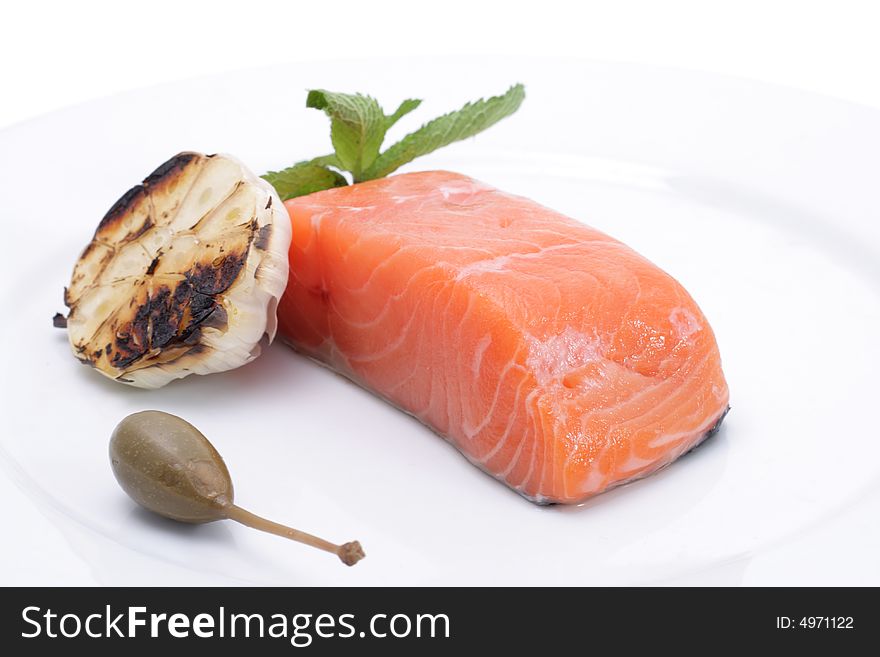 Fresh salmon, garlic and green on a plate. Isolated on a white background. Fresh salmon, garlic and green on a plate. Isolated on a white background