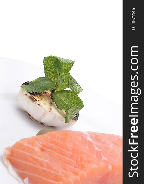 Fresh salmon, garlic and green on a plate. Isolated on a white background. Fresh salmon, garlic and green on a plate. Isolated on a white background
