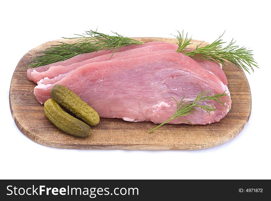 Raw pork schnitzel with pickled cucumbers and dill on a wooden hardboard isolated on white