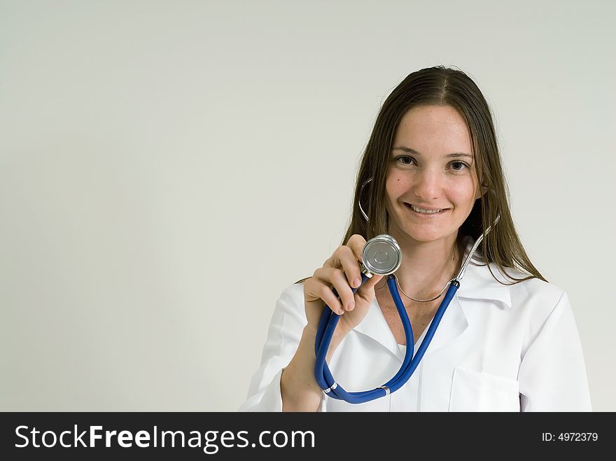 Young female doctor holding up her stethoscope and smiling. Isolated. Young female doctor holding up her stethoscope and smiling. Isolated.