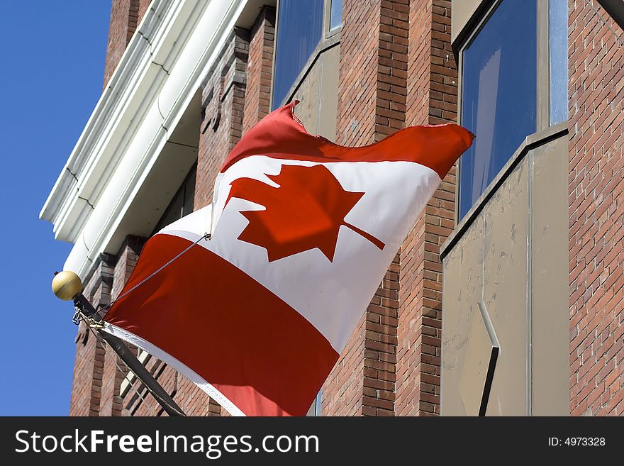 Canadian flag in front of administrative building with blue sky