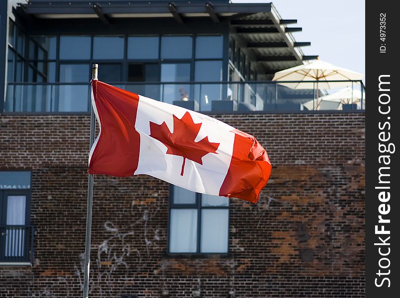 Canadian flag in front of administrative building with blue sky