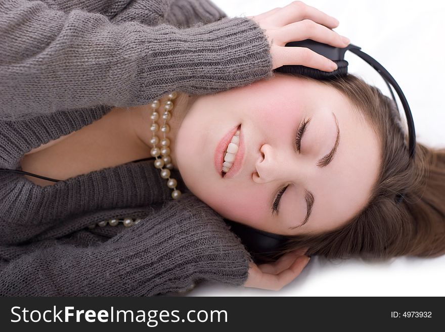 Nice brunette with big earphones lying on the floor on white background. Nice brunette with big earphones lying on the floor on white background