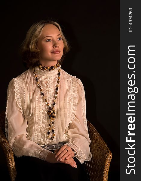 Beautiful woman in dream of happiness sitting in the cane-chair (isolated on black). Beautiful woman in dream of happiness sitting in the cane-chair (isolated on black)