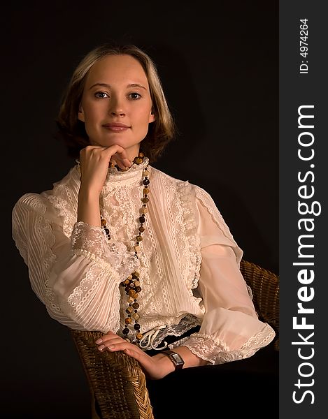 Smiling woman at armchair look ahead (isolated on black)