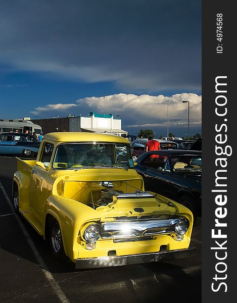 A classic 50s yellow Ford hotrod truck captured at a car show. A classic 50s yellow Ford hotrod truck captured at a car show