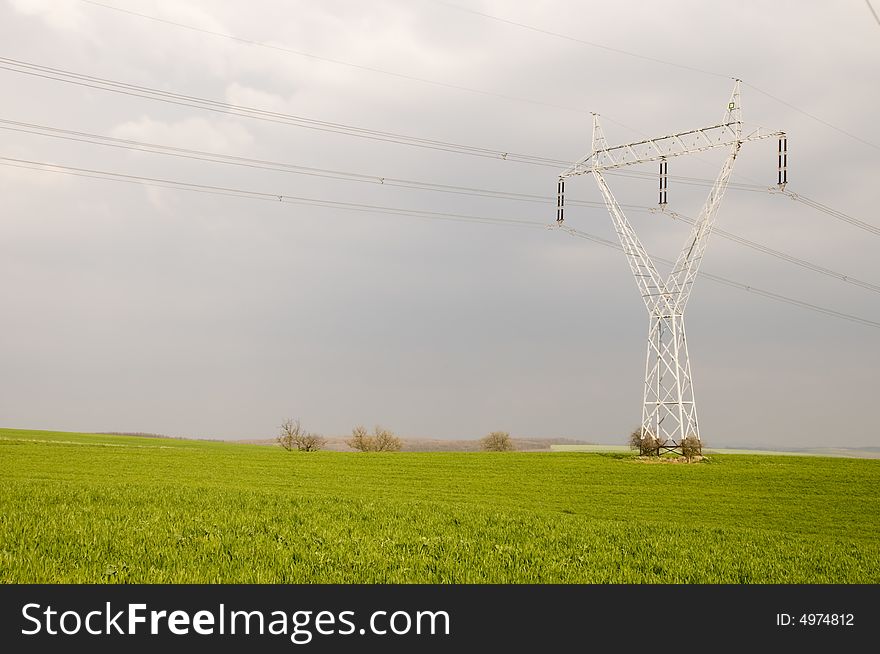 Many electricity pylons with wire in the green fields. Many electricity pylons with wire in the green fields
