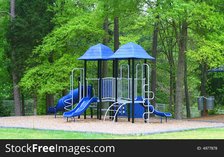 Bright childrens playground surrouned by green trees