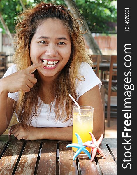 Asian girl having a glass of orange juice at an outdoor cafe. Asian girl having a glass of orange juice at an outdoor cafe.