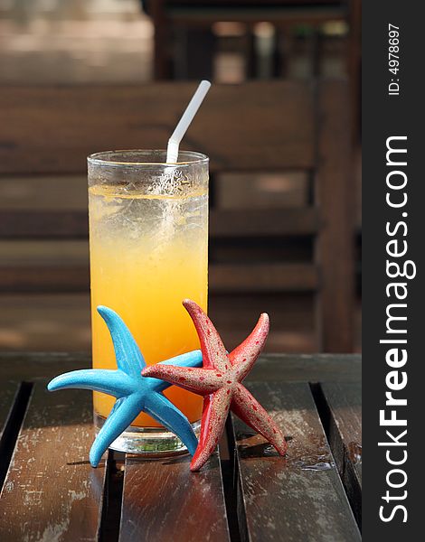 Glass of orange juice with starfish next to it.