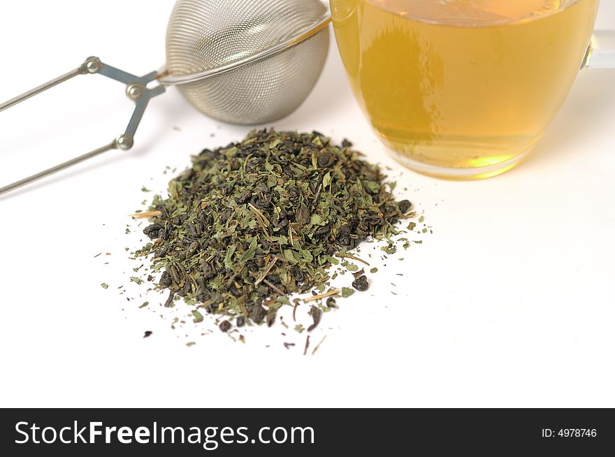 Green tea with strainer and leaves on a white surface. Green tea with strainer and leaves on a white surface