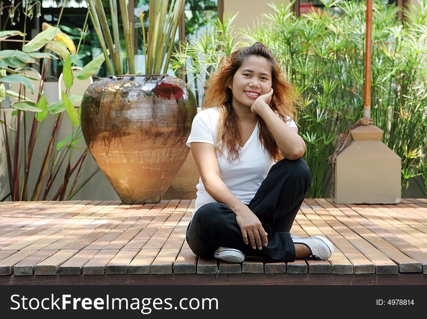 Portrait of an attractive young Thai girl sitting on a deck. Portrait of an attractive young Thai girl sitting on a deck.