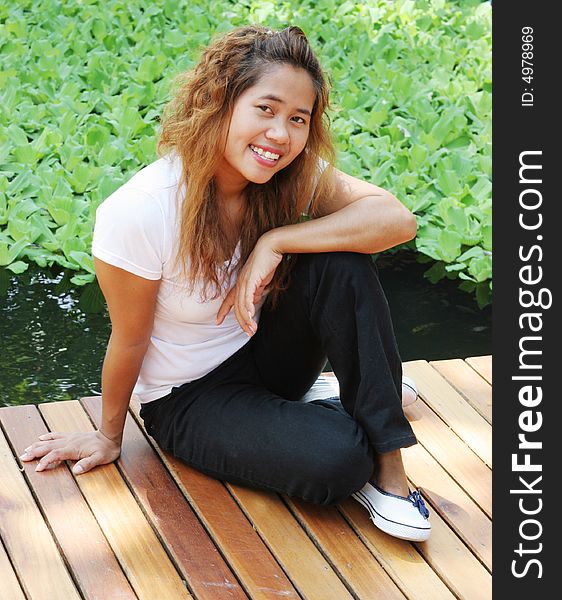 Portrait of a happy Asian woman sitting on a deck. Portrait of a happy Asian woman sitting on a deck.