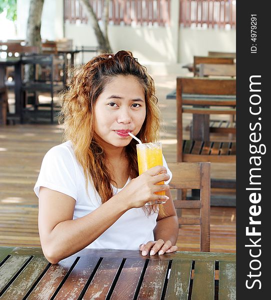 Pretty Asian girl having a drink at a cafe. Pretty Asian girl having a drink at a cafe.