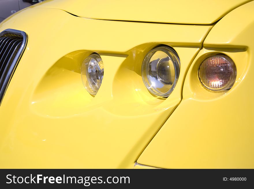 Close-up of a headlight on yellow modern car. Close-up of a headlight on yellow modern car