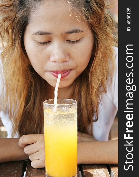 Close-up portrait of a pretty Thai woman drinking juice.