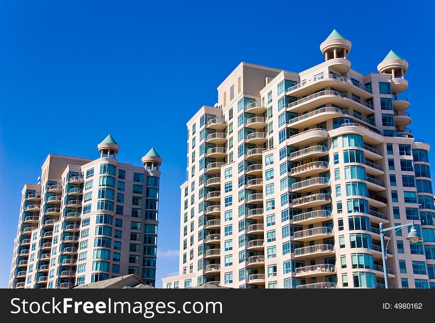 Two condominiums with many balconies on a sunny day with blue sky. Two condominiums with many balconies on a sunny day with blue sky