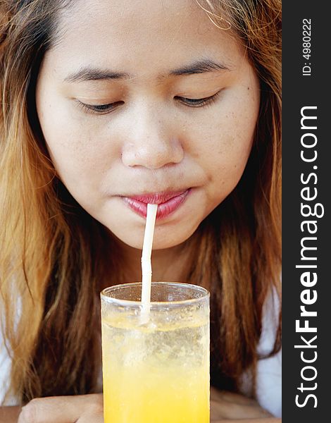 Close-up portrait of a pretty Thai woman drinking juice.