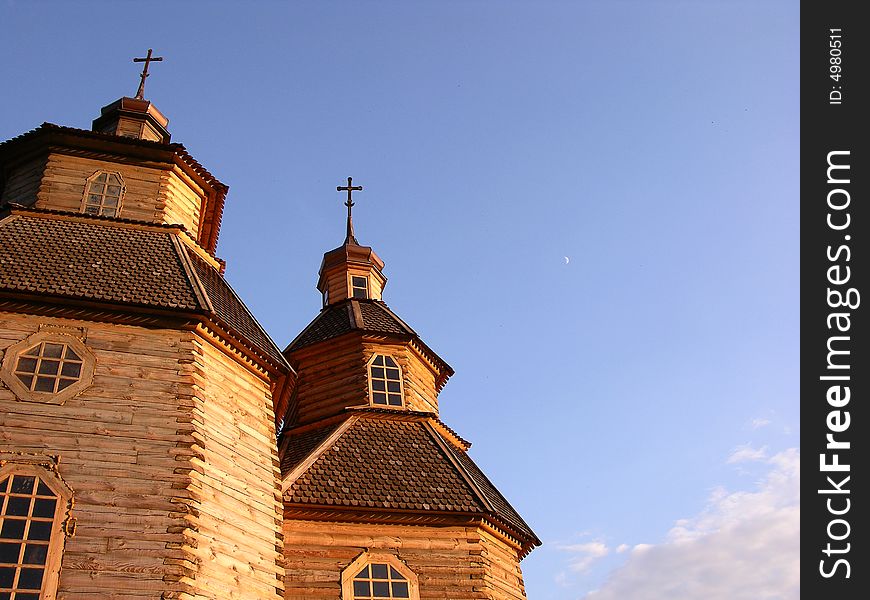 The moon rising over church steeple against a blue sky. The moon rising over church steeple against a blue sky