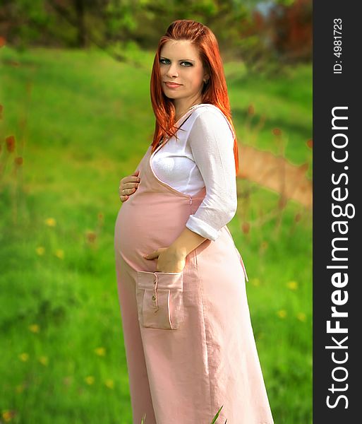 Beautiful and young pregnant girl walks on spring park: a good illustration for magazine about pregnant women and for women