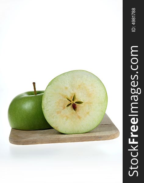 A fresh cut green apple placed on wooden cutting board. A fresh cut green apple placed on wooden cutting board