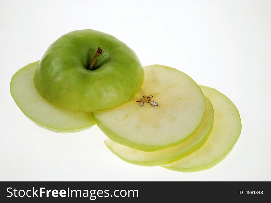 Cut fresh green apple slices are placed on each other over white