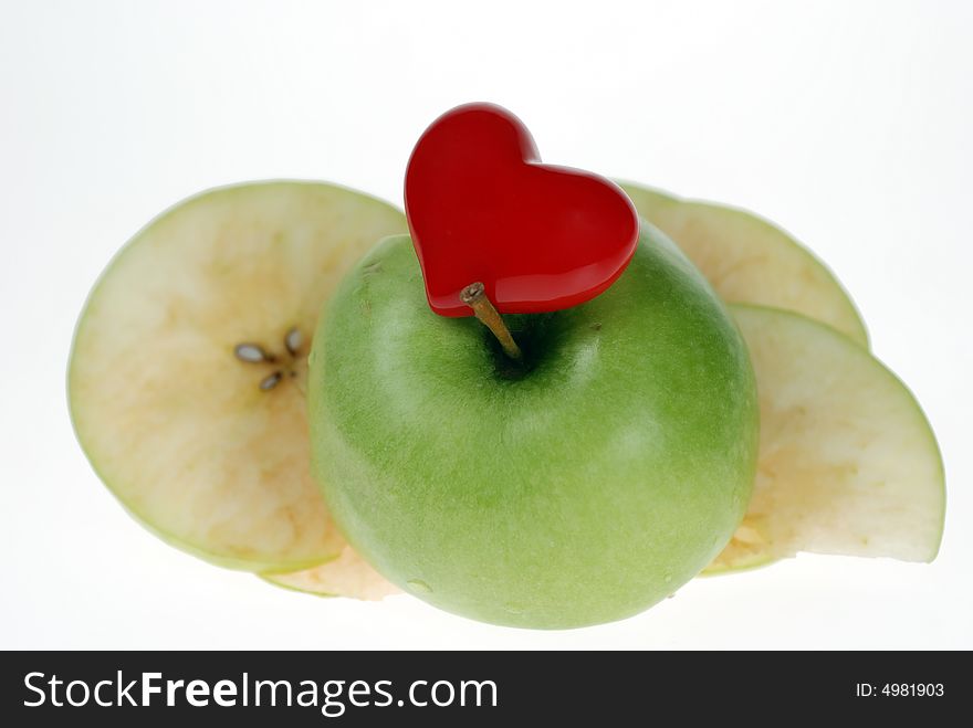 An apple together with red heart infront of apple slices over white. An apple together with red heart infront of apple slices over white