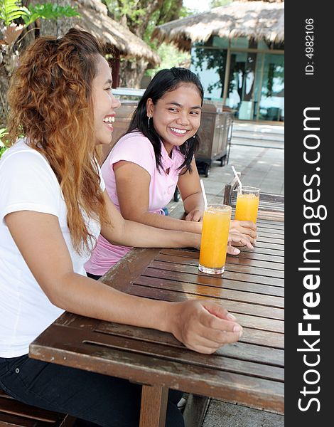 Two pretty Asian friends having a drink at a cafe.