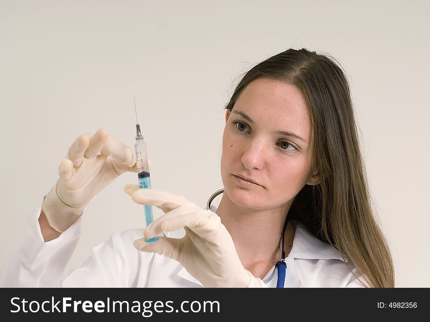 Young female doctor with gloved hands tapping a syringe. Isolated. Young female doctor with gloved hands tapping a syringe. Isolated.