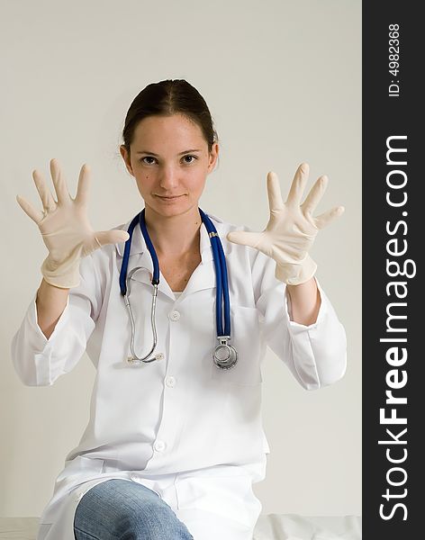 Young female doctor holding out her gloved hands. Isolated. Young female doctor holding out her gloved hands. Isolated.