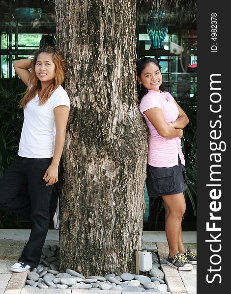Portrait of two pretty Thai women leaning on a tree. Portrait of two pretty Thai women leaning on a tree.