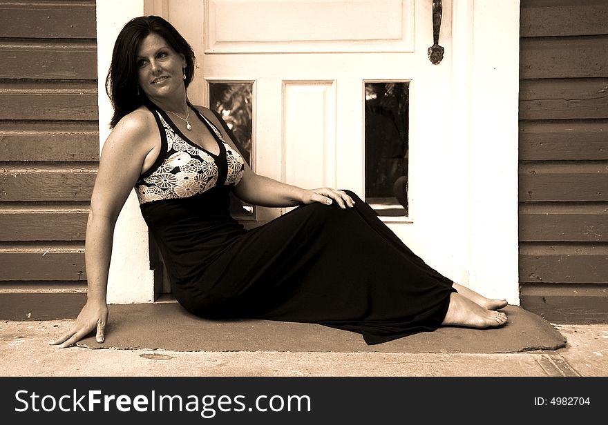 Black and white of a woman sitting in the doorway with tropical island type architecture. Black and white of a woman sitting in the doorway with tropical island type architecture