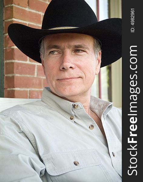 A closeup of a man in a cowboy hat relaxing on a porch. A closeup of a man in a cowboy hat relaxing on a porch.