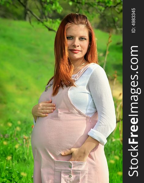 Beautiful and young pregnant girl walks on spring park: a good illustration for magazine about pregnant women and for women