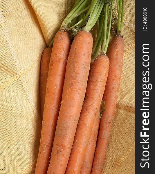 Fresh bunch of carrots on yellow tablecloth