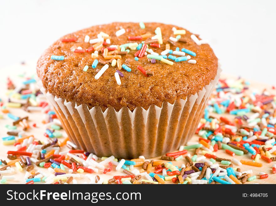 Tasty muffin with colorful sprinkles, isolated