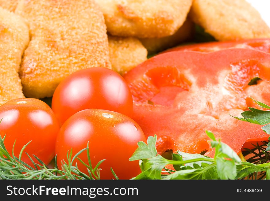 Appetizing fried chicken nuggets  with tomatoes, cucumber and pepper on salad leaves. Close-up. Selective focus. Appetizing fried chicken nuggets  with tomatoes, cucumber and pepper on salad leaves. Close-up. Selective focus.