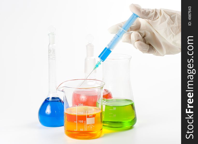 Various colorful flasks and hand in glove over white background