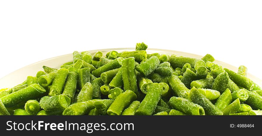 Frozen string beans in plate close-up over white