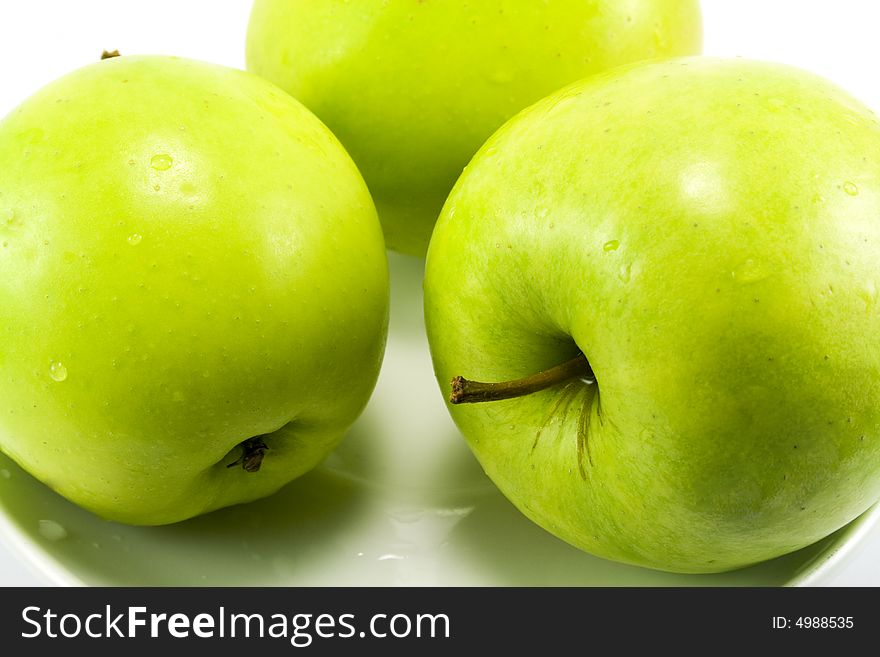 Close-up of three green apples on a plate