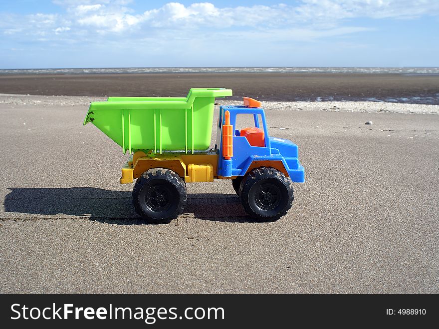 Colorful plastic toy truck  in the sand