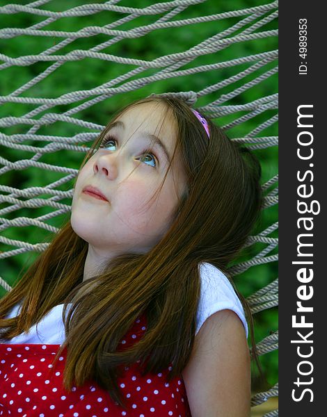 Eight year old child daydreaming in a hammock