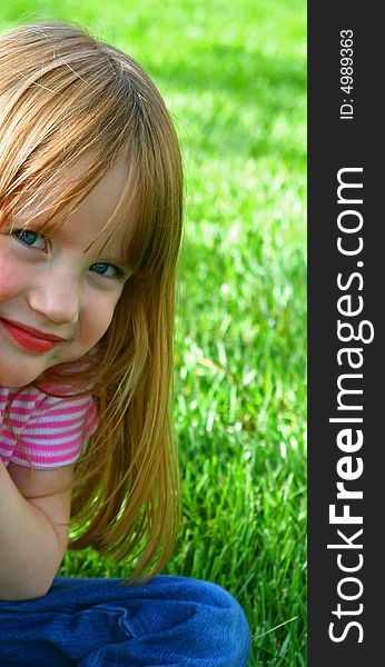 Smiling little girl sitting in the grass. Smiling little girl sitting in the grass