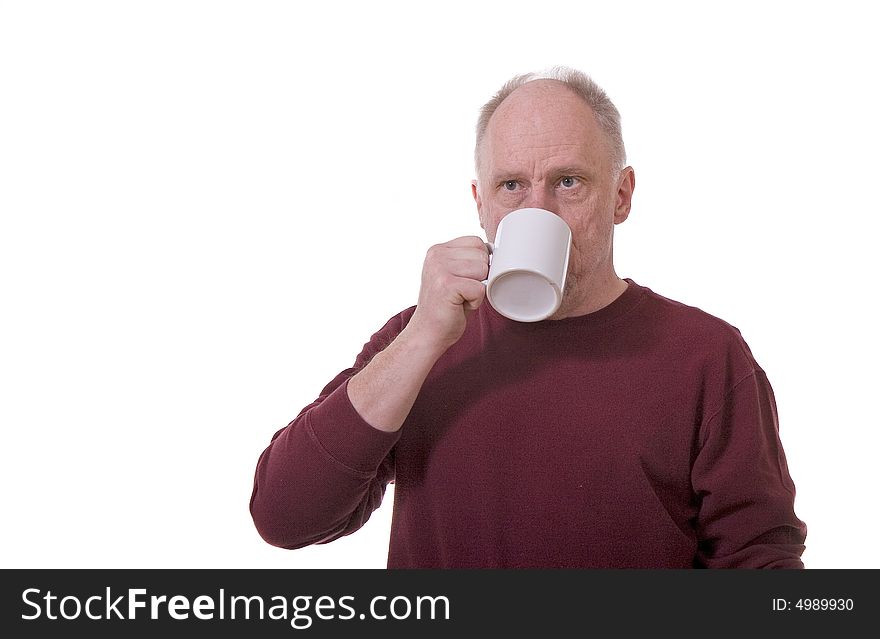 An older guy in a red shirt on a white background drinking coffee from a white mug. An older guy in a red shirt on a white background drinking coffee from a white mug