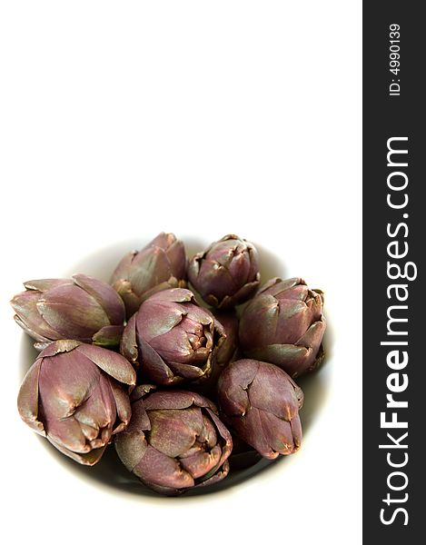 Purple artichokes in a bowl, isolated on white background