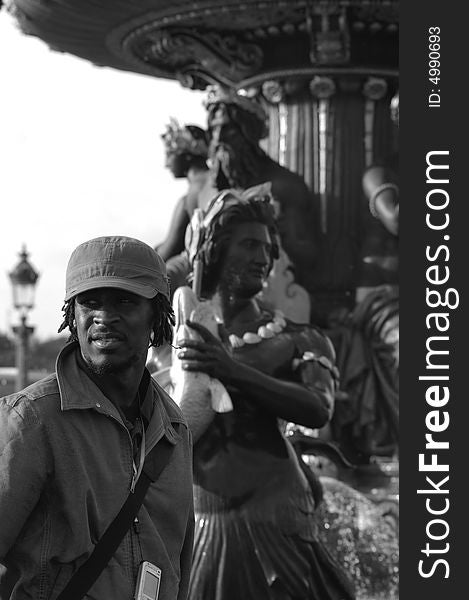 Black and white picture of a young african man near of a fountain located in Paris. Black and white picture of a young african man near of a fountain located in Paris.
