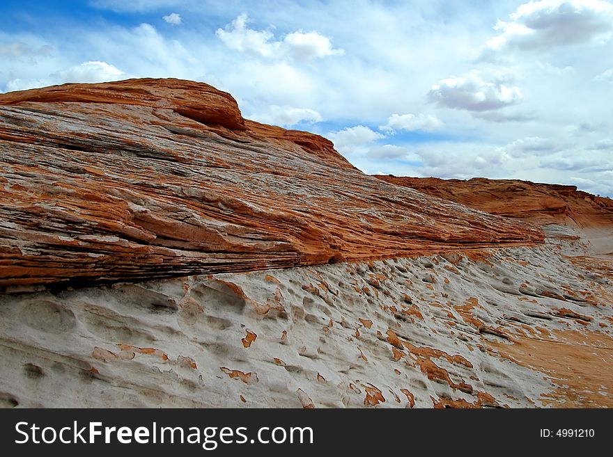 Close-up view of weathered sandstone formations against a blue cloud covered sky. Close-up view of weathered sandstone formations against a blue cloud covered sky.